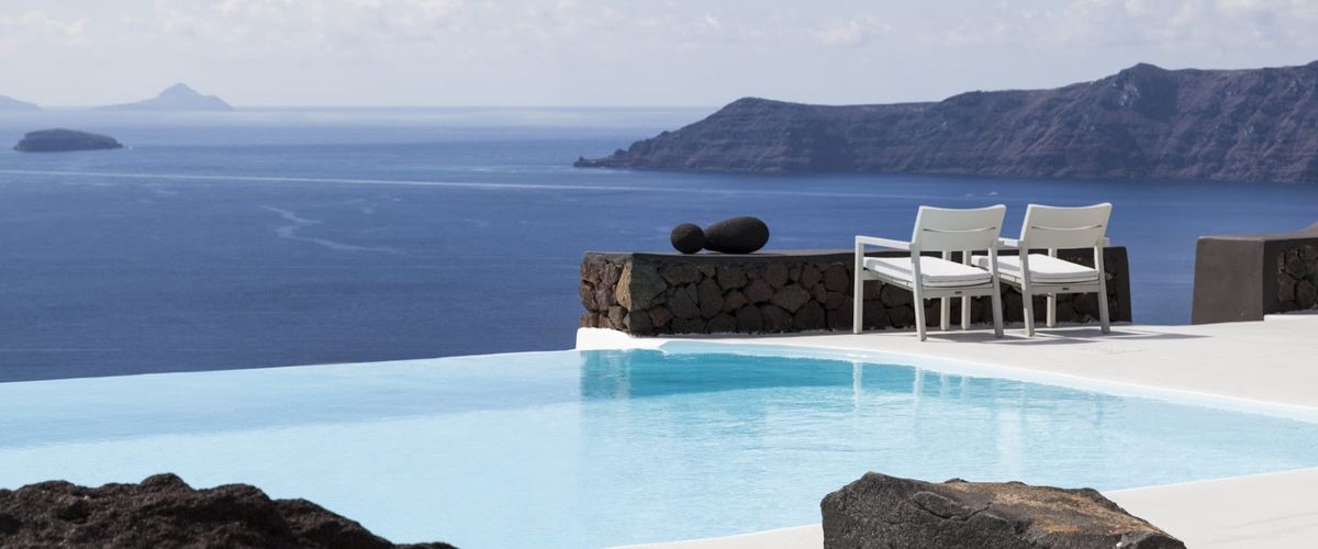 Santorini caldera panorama — white-washed Cycladic buildings cascading down the volcanic cliff above the deep blue Aegean Sea